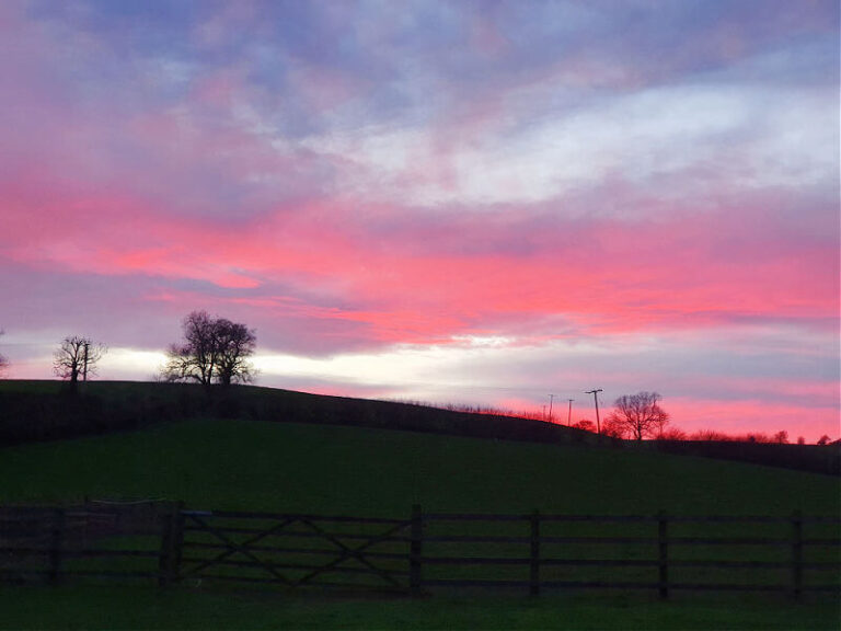 red sky over the hills with fence in the foreground