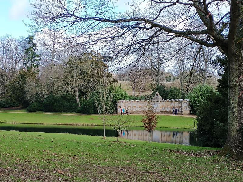 long distance view of arc of statues at Stowe and reflection in water