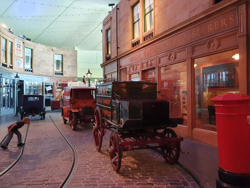 reproduction of old cobbled shopping street with old horse pulled wagons and cars