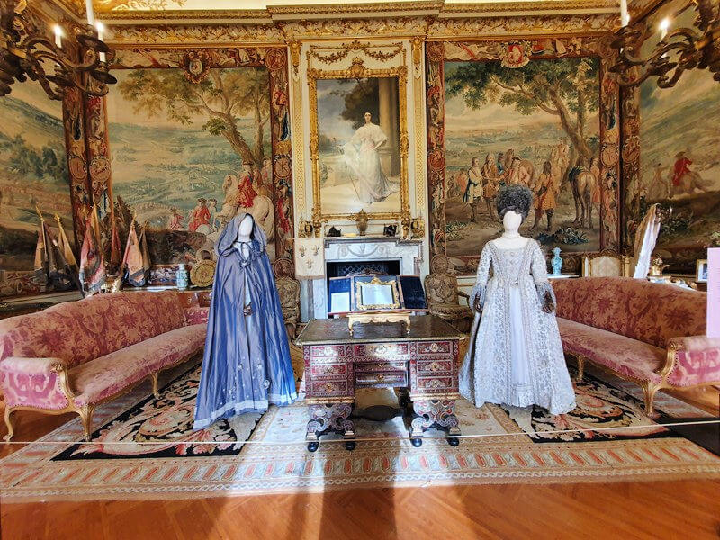 2 Queen Charlotte dresses and long cape on display in Blenheim palace room