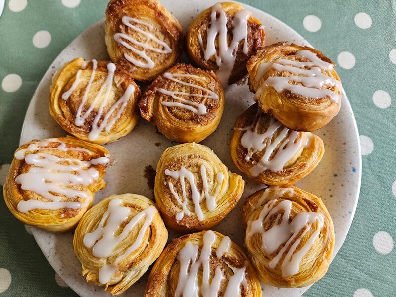 icing drizzled on homemade puff pastry cinnamon buns