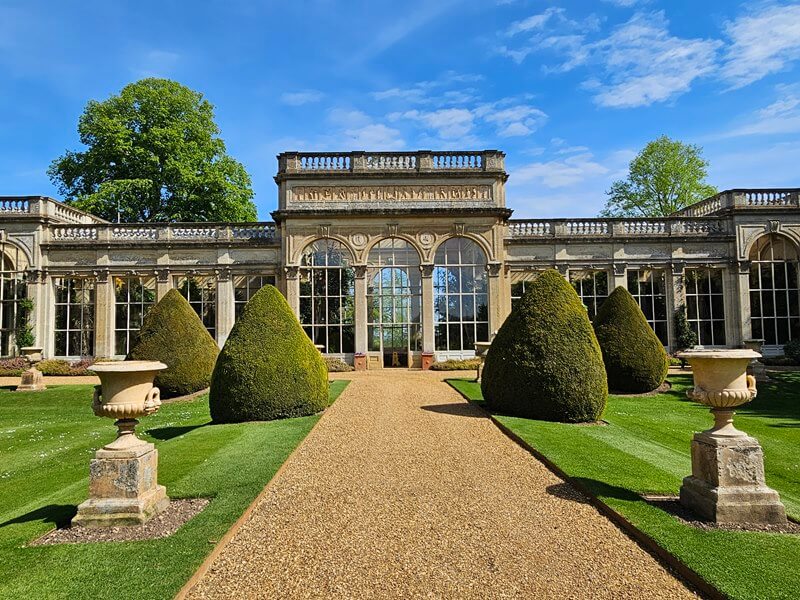 looking back at the orangery with urns and topiary along path