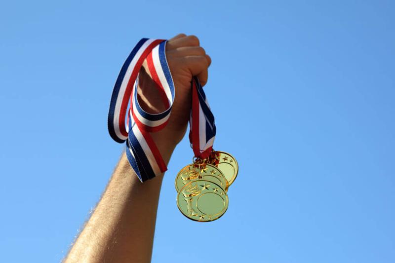 hand holding up olympic medals