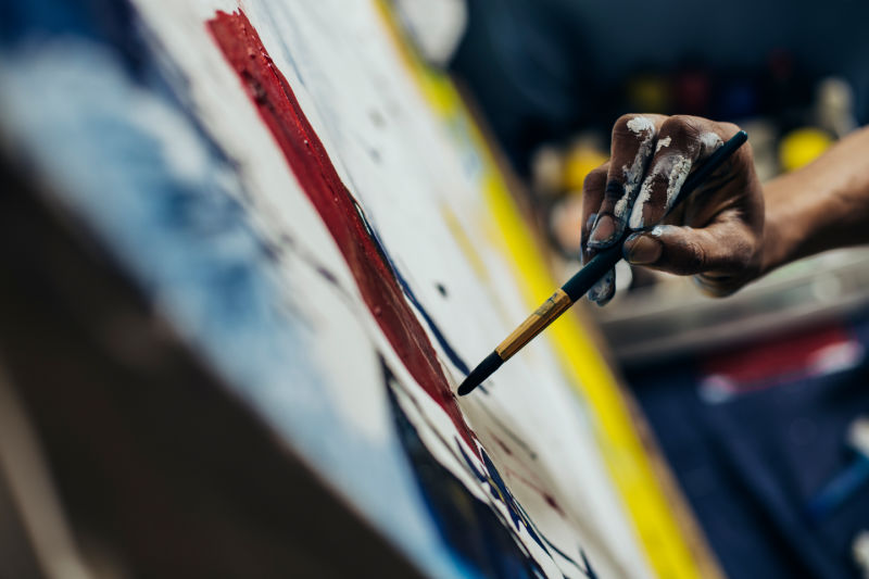 man's hand painting on a canvas close up