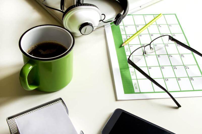 monthly calendar with stationery and glasses on desk