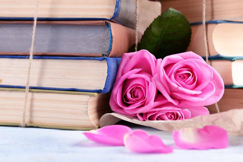 old books pile with pink roses