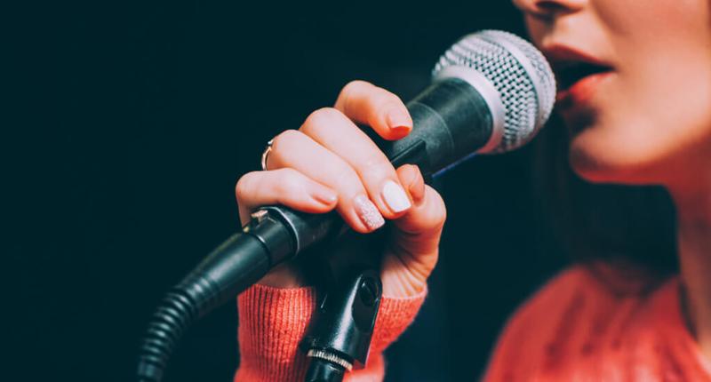 woman singer with red lipstick singing in to a microphone she's holding