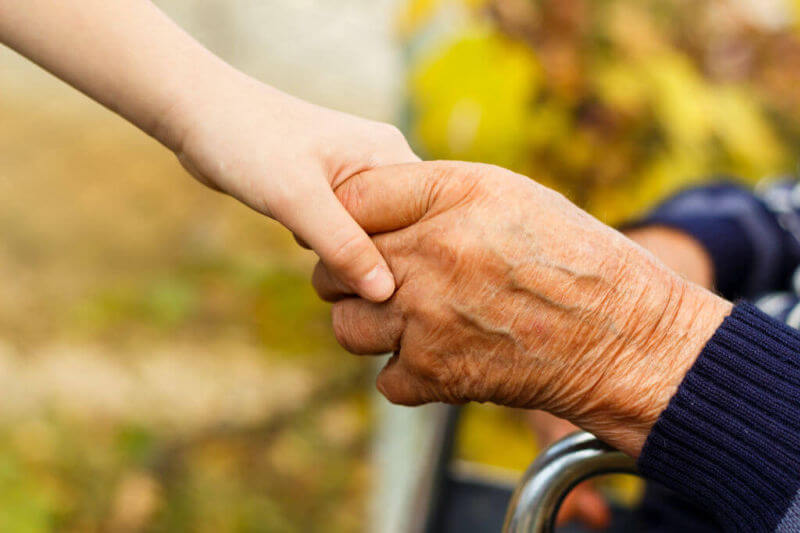 young hand holding hands with an elderly person's hand