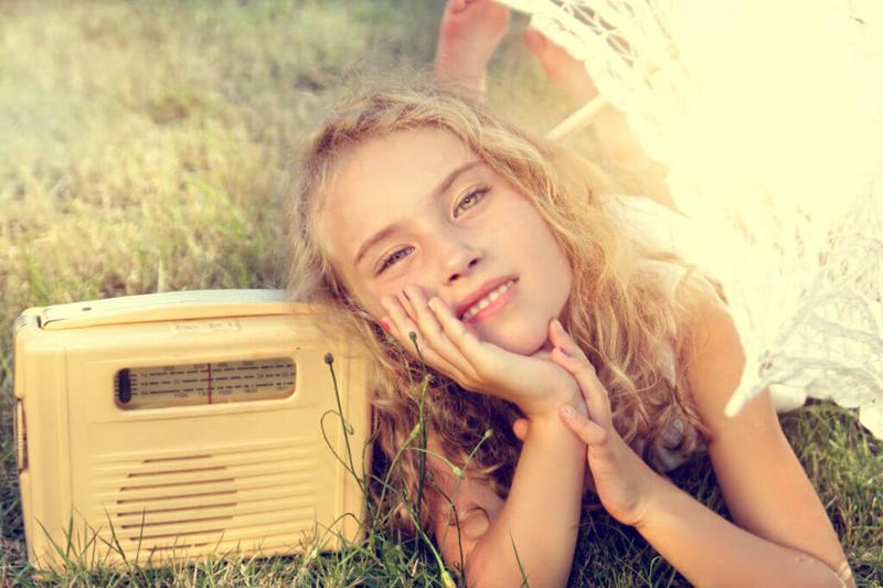 young woman listening to a radio in summer sun lying on the ground