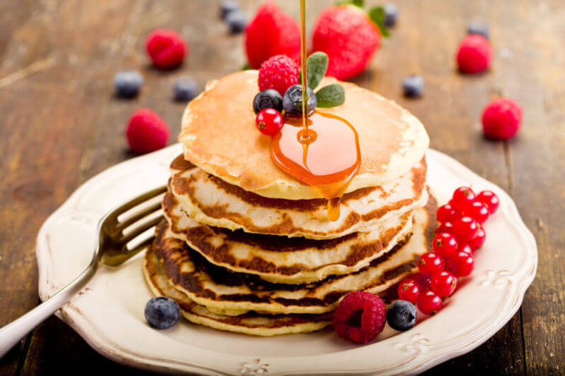 american pancake stack with syrup and fruit