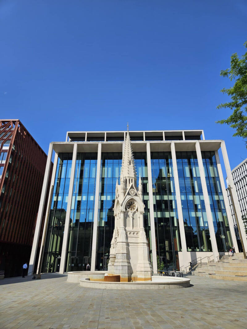 Spire statue in front of modern glass building